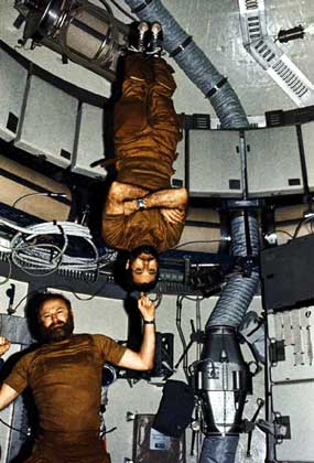 ВНУТРИ СТАНЦИИ командир экспедиции Дж.Карр указательным пальцем держит на весу пилота У.Поуга - наглядная иллюстрация невесомости в космосе. Фотоснимок сделан Э.Гибсоном. Три космонавта провели почти три месяца в 1973-1974 на борту космической станции Скайлэб. Этого времени им вполне хватило, чтобы отрастить бороды.