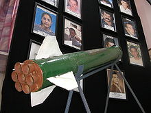 Sderot - A Qassam rocket is displayed in Sderot town hall against a background of pictures of residents killed in rocket attacks.jpg