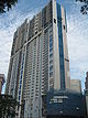 Ground-level view of a box-like, 50-storey tower with a rectangular cross section and a blue stripe on the lateral siding