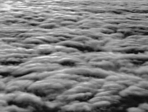 Вид сверху на слоисто-кучевые облака. В верхней части снимка видны высоко-слоистые облака, сквозь которые просвечивает солнце (снимок с самолёта).