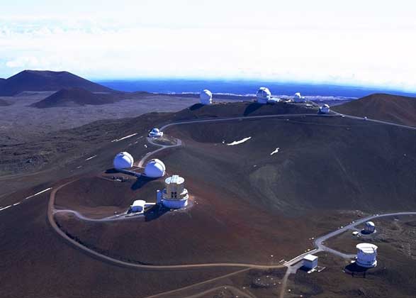 НА ВЕРШИНЕ МАУНА-КЕА, древнего вулкана на Гавайях, расположились десятки телескопов. Астрономов привлекают сюда большая высота и очень сухой чистый воздух. Внизу справа сквозь открытую щель башни хорошо видно зеркало телескопа Кек I, а внизу слева - строящуюся башню телескопа Кек II.