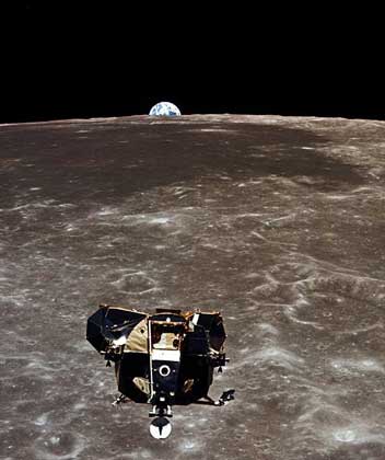 ВЗЛЕТНАЯ КАБИНА ИГЛ НАД ПОВЕРХНОСТЬЮ ЛУНЫ. Снимок сделан во время исторического полета Аполлона-11 М.Коллинзом из отсека экипажа основного блока. Виден восход Земли над лунным горизонтом.