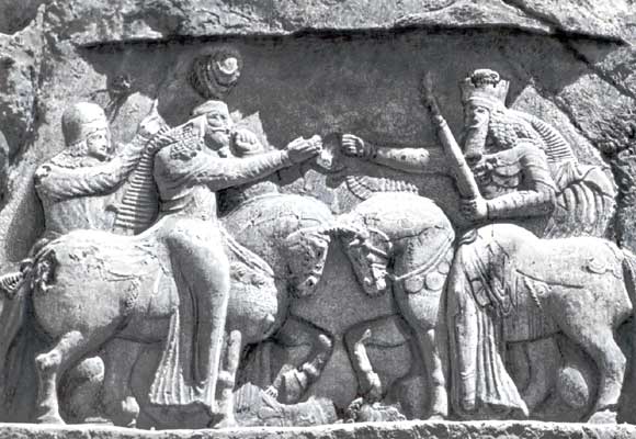 Ахурамазда, попирающий Ангро-Майнью копытами своего коня и вручающий символ царской власти шаху Арташиру.