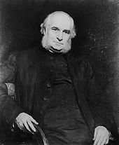 An old man in half-figure on a chair, with his right arm over the back, facing the viewer. His hair and large muttonchops are white, his attire is black and simple.
