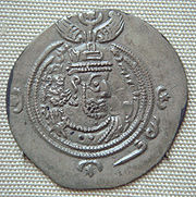 A silver coin with a face of Khosrau II surrounded by a double ring and some symbols