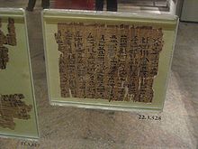 Музейная выставка древнего фрагмента папирусного документа за стеклом, с надписью черными чернилами