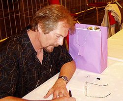 Майкл Уэлан дает автографы на 63-м конвенте Worldcon в Глазго в августе 2005 г.