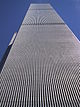 Aerial view of two 110-story twin towers; the building have gray, steel exteriors, and the structure on the left is topped by a large antenna. Several skyscrapers are visible surrounding the two towers.