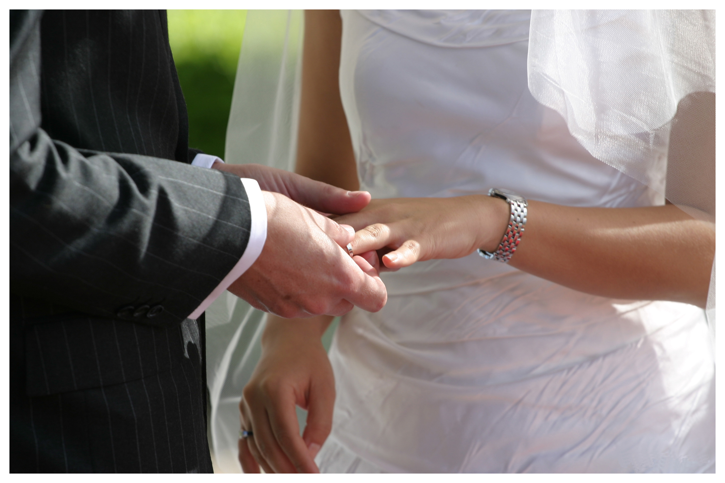 Первое замужество. Жених одевает кольцо невесте. Руки молодоженов с кольцами. Обручальные кольца на руках. Невеста на руках у жениха.